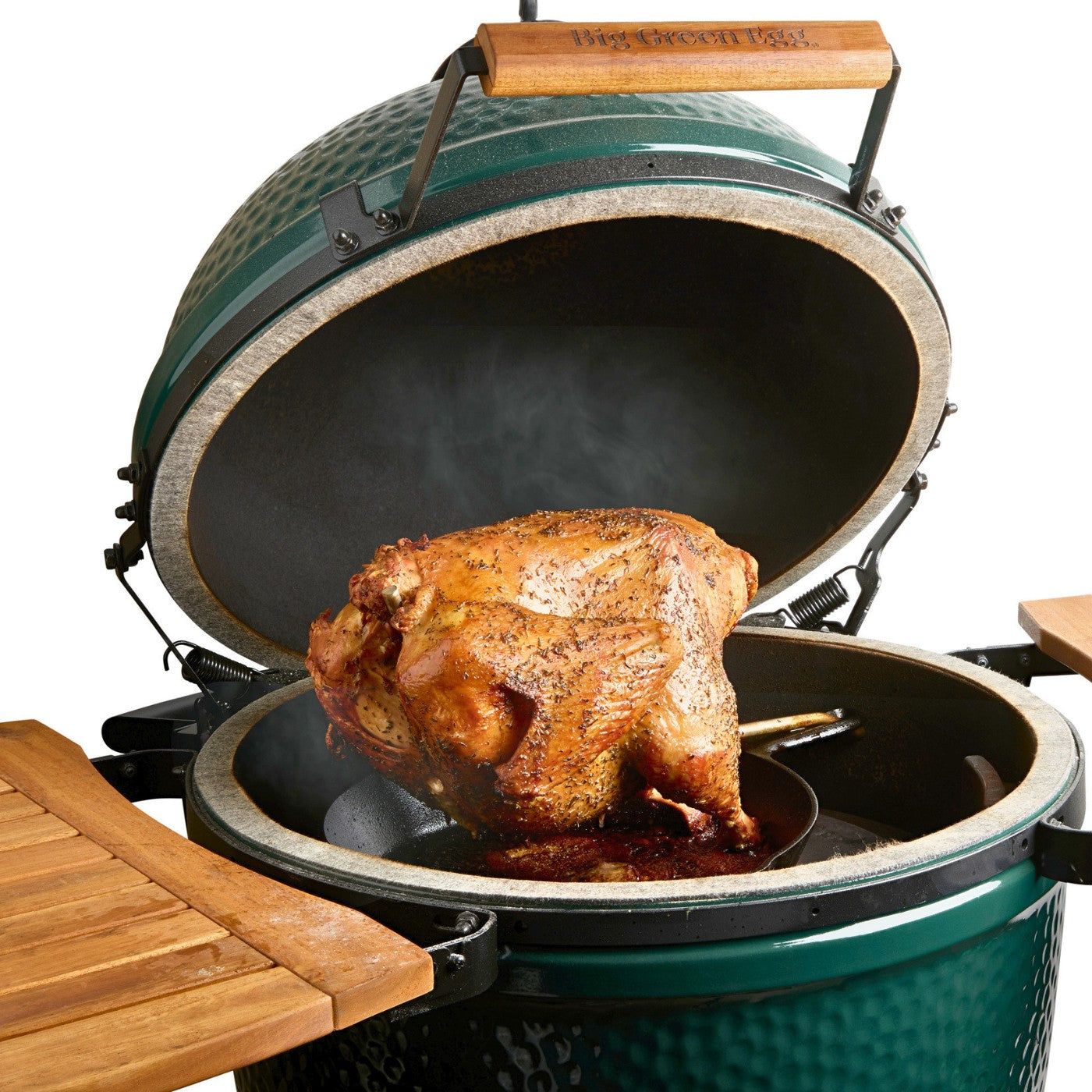 Juicy turkey hanging on the PoulTree Turkey Talon over a cast iron skillet in a Big Green Egg