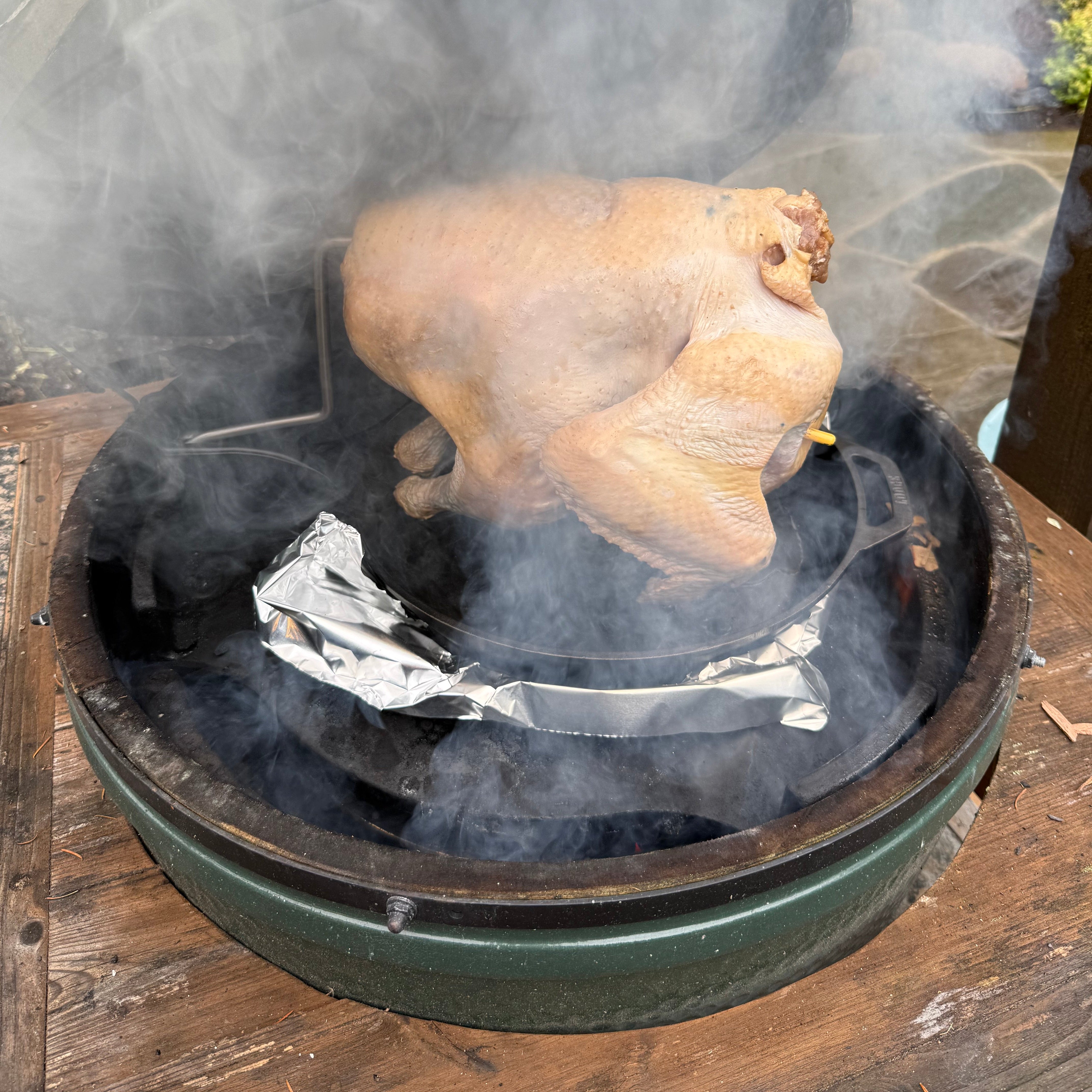 Roasted turkey on a Green Egg grill with smoke rising