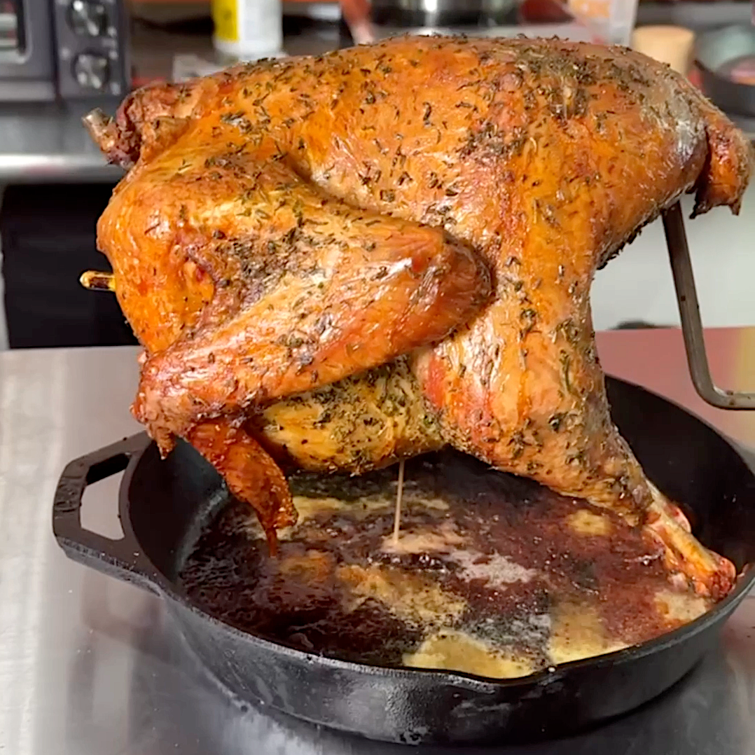 Close-up of crispy, golden turkey skin on a bird roasted upright in a cast iron skillet